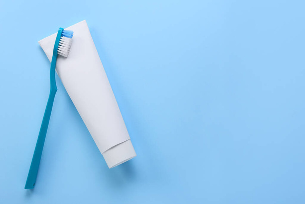 Tubo con pasta de dientes y cepillo sobre fondo azul - Foto, imagen
