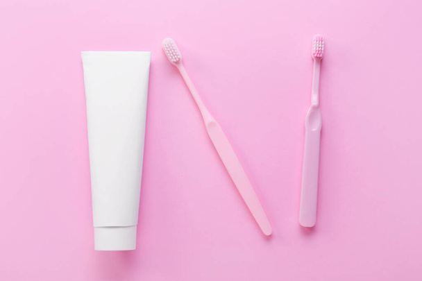Cső fogkrém és kefék rózsaszín háttér - Fotó, kép