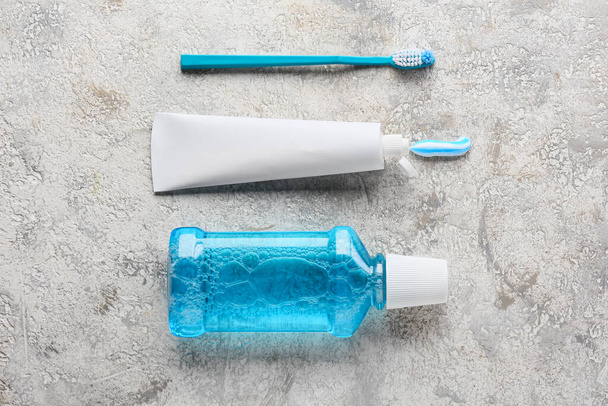 Tube with tooth paste, brush and mouthwash on grey background - Foto, Imagen