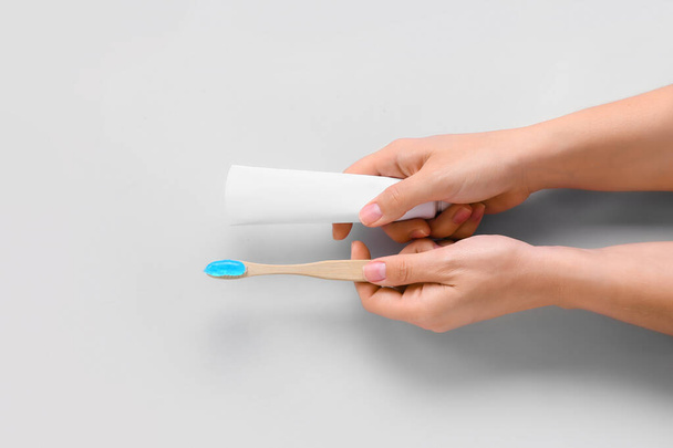 Γυναικεία χέρια με οδοντόβουρτσα και πάστα σε λευκό φόντο - Φωτογραφία, εικόνα