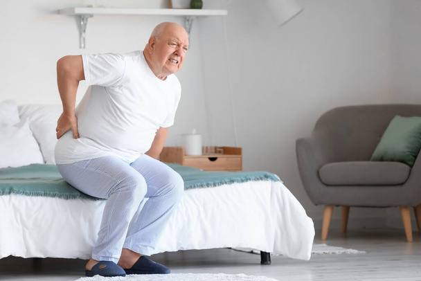 Idős férfi szenved hátfájás az ágyban otthon - Fotó, kép