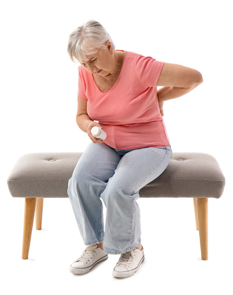 Senior woman with bottle of pills suffering from back pain on white background - Photo, Image