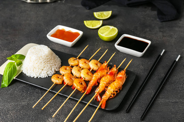 Bord met gegrilde garnalen spiesen, rijst en sauzen op zwarte achtergrond - Foto, afbeelding