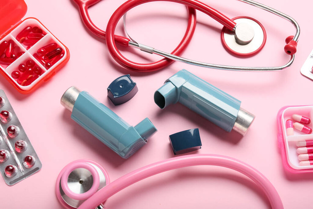 Asthma inhalers, stethoscopes and pills on pink background, closeup - Photo, Image