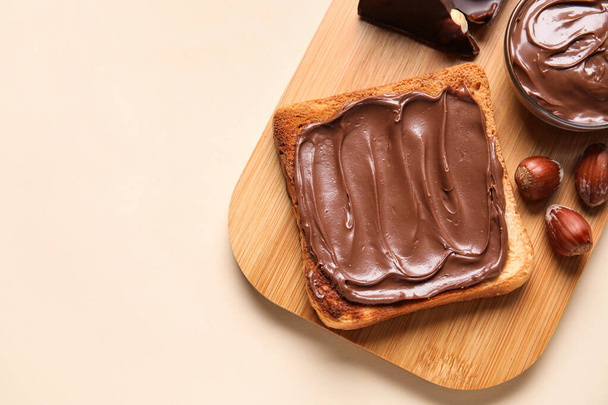 Tábla kenyér csokoládé paszta és mogyoró bézs alapon, közelkép - Fotó, kép