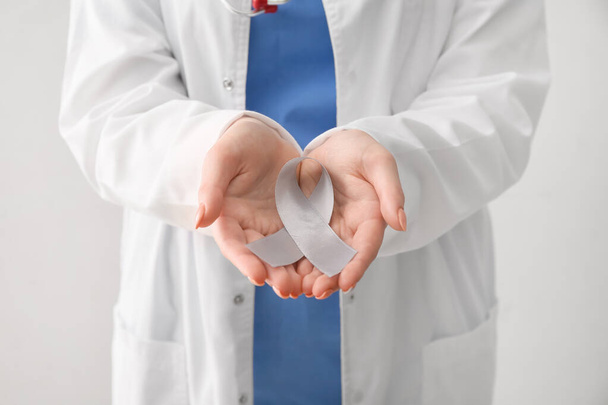 Médecin femme avec ruban de sensibilisation à la maladie de Parkinson sur fond clair, gros plan - Photo, image