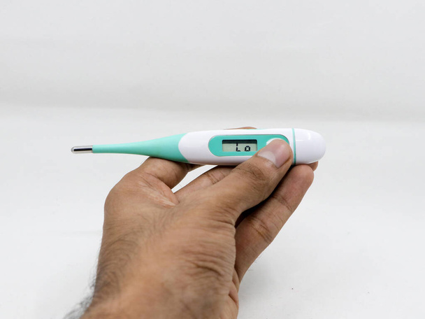 un thermomètre numérique à faible lecture, entre les mains d'une personne isolée dans un fond blanc - Photo, image