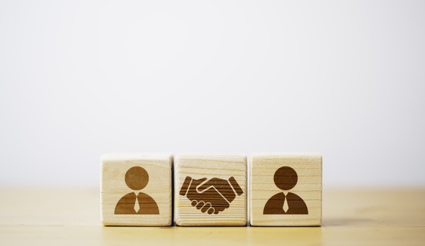 取引と契約の概念のための人間のアイコンの前に木製のキューブブロック上の印刷画面握手の図面. - 写真・画像