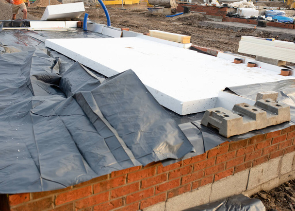 Wasserdichte Membran und Fußbodendämmung, um den Wärmeverlust in Zukunft zu verringern, wird von Bauarbeitern während des Baus eines neuen Wohnhauses angebracht - Foto, Bild