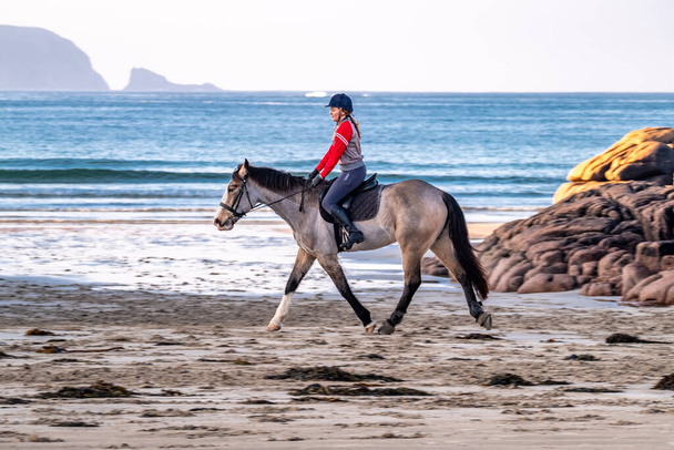 Burtonport, County Donegal, Ireland - December 18 2021 : Patricia Ward is riding her horse on the beach - Фото, зображення