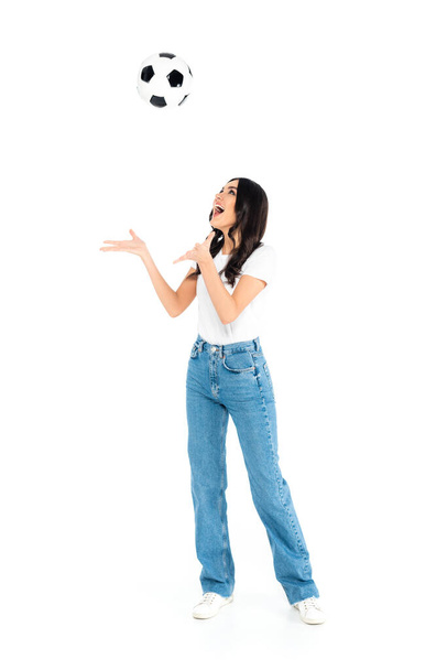 full length view of excited woman in jeans playing with soccer ball on white - Photo, Image