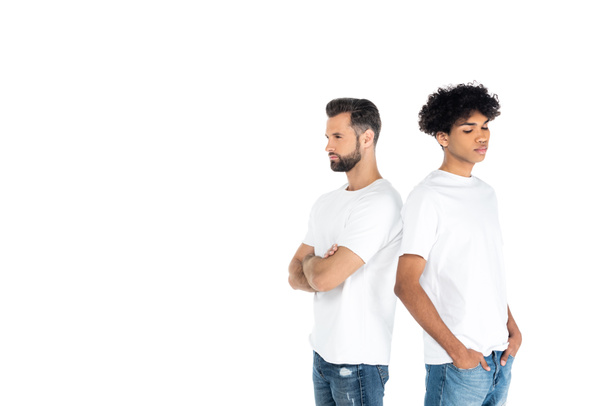 offended interracial men standing back to back with crossed arms and hands in pockets isolated on white - Foto, Imagem