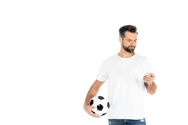 positive man with soccer ball messaging on mobile phone isolated on white - Фото, изображение