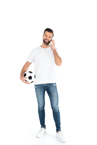 full length view of man with soccer ball talking on cellphone on white - Фото, изображение