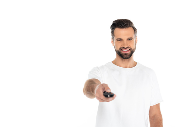 cheerful man clicking channels on tv remote controller isolated on white - Фото, изображение