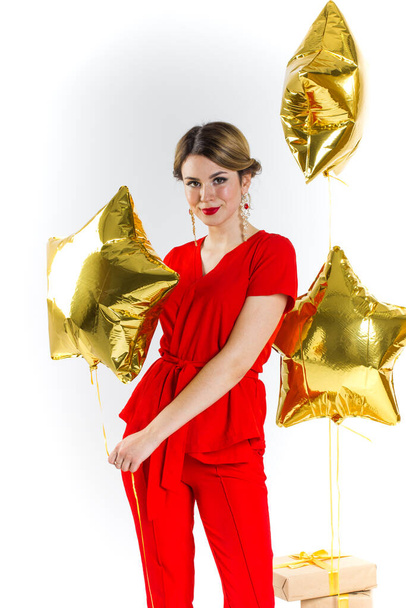 Joyful woman holding a golden stars on a white background. Celebrating birthday, anniversary. Shopping for holiday concept, saleout, black friday, cyber monday - 写真・画像