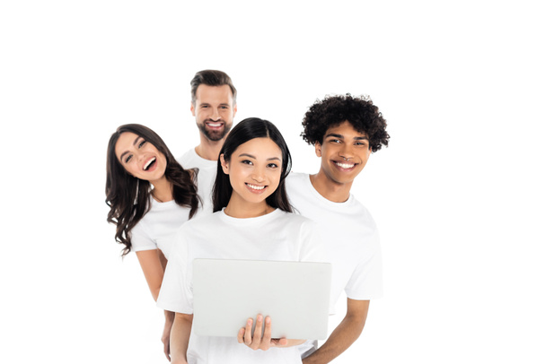 cheerful multiethnic friends looking at camera near asian woman with laptop isolated on white - Φωτογραφία, εικόνα