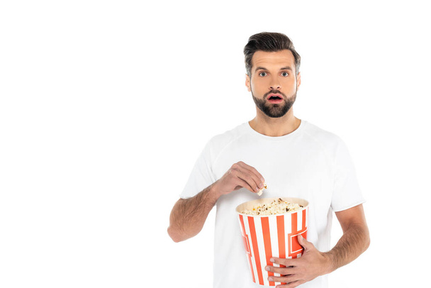 astonished man watching movie and eating popcorn isolated on white - Foto, imagen
