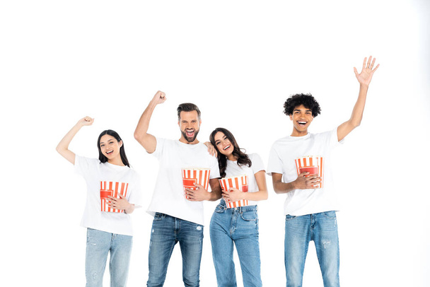 smiling african american man waving hand near excited friends with popcorn showing win gesture isolated on white - Foto, Imagem