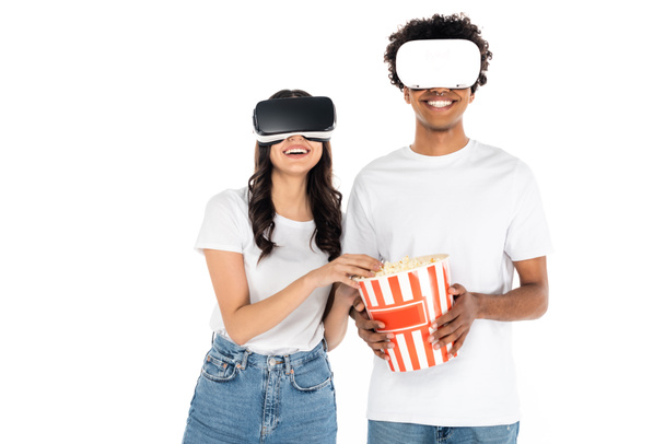 ευτυχισμένο διαφυλετικό παιχνίδι ζευγάρι σε VR ακουστικά κοντά κουβά για ποπ κορν που απομονώνονται σε λευκό - Φωτογραφία, εικόνα