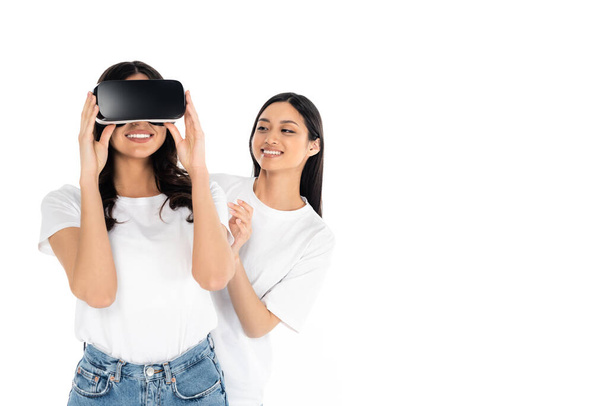 jong aziatische vrouwen glimlachen in de buurt vriend gaming in vr headset geïsoleerd op wit - Foto, afbeelding