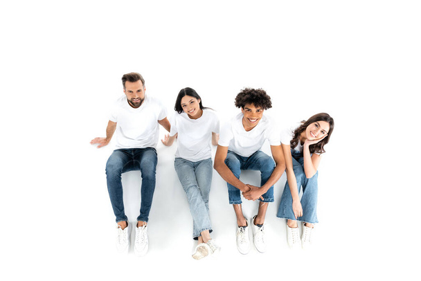 top view of happy multiethnic friends looking at camera while sitting on white - Fotoğraf, Görsel