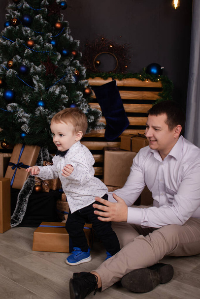 little toddler boy with man near christmas tree and decoration. son and father on christmas eve. new year. single father. incomplete family - Zdjęcie, obraz