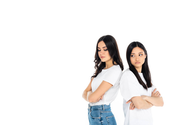 offended interracial women standing back to back with crossed arms isolated on white - Foto, Imagen