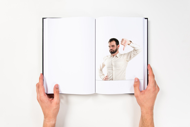 Jeune homme avec les pouces vers le bas imprimé sur le livre
 - Photo, image