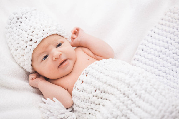 Cute newborn baby girl in a knitted hat on the white backdround - Фото, изображение