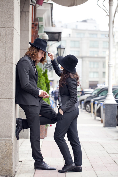 Young happy stylish couple in black hats posing on the street - Zdjęcie, obraz