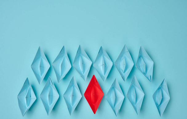group of paper boats on a blue background. concept of a strong leader in a team, manipulation of the masses, following new perspectives, collaboration and unification. Startup - Photo, Image
