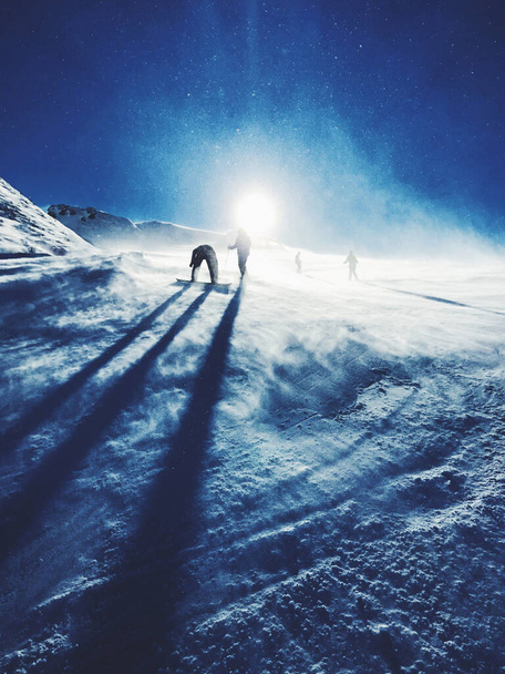 Silhouettes of snowboarders on a ski slope with a snowy sun - Foto, afbeelding