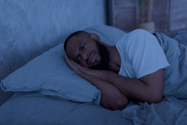 Μαύρος ξαπλωμένος στο κρεβάτι και σκεπτόμενος τη νύχτα - Φωτογραφία, εικόνα