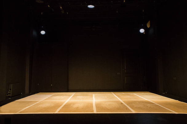 Empty black stage with thin plywood floor illuminated by lamps - Zdjęcie, obraz