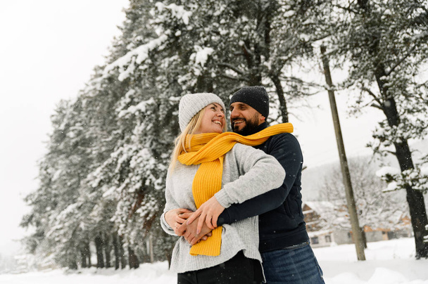 Attractive man and woman cuddling in the frosty forest. Adult couple in sweaters have fun on walk. Romantic date in winter time.Winter lovestory - Foto, immagini