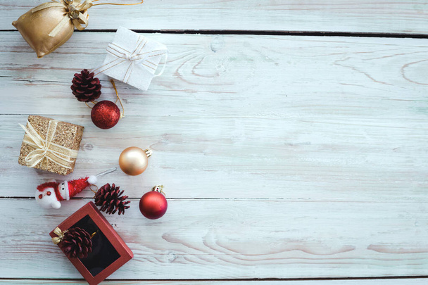 Bovenaanzicht van kerstcompositie met rode en gouden bal, geschenkdozen, sneeuwpop op houten achtergrond en kopieerruimte. Accessoires van Kerstmis en Nieuwjaar concept. - Foto, afbeelding