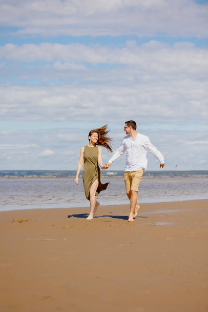 a couple of a man and a woman are walking on the beach or running along the sand along the seashore. beautiful and young  - Foto, immagini