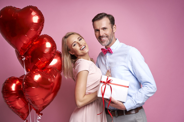 Caucasian couple holding a bunch of red balloons and a gift box - Foto, Imagem