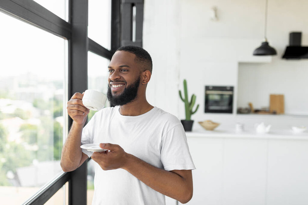 Smiling African American man drinking coffee looking through window - Fotografie, Obrázek