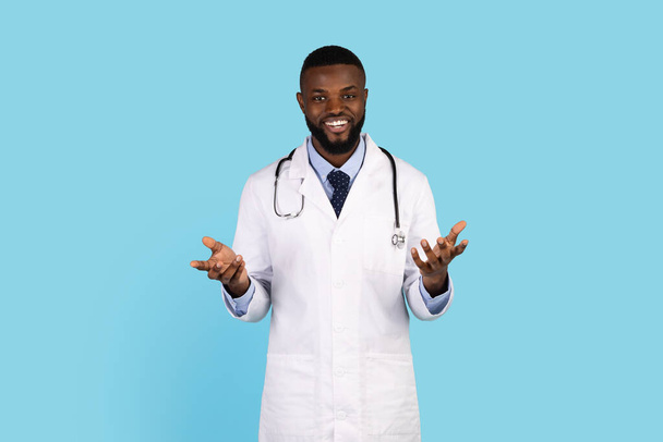 Portrait Of Male African American Doctor In Uniform Posing On Blue Background - Fotó, kép