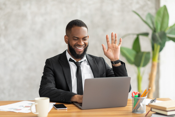 Μαύρος άνδρας που έχει βιντεοκλήση χρησιμοποιώντας υπολογιστή και χαιρετώντας - Φωτογραφία, εικόνα