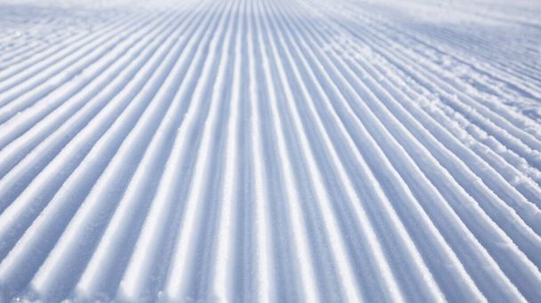 rechte rijstroken van een vers geprepareerde skipiste. Sneeuw na het passeren van de sneeuwkat. Winterseizoen, skigebied, koud besneeuwd weer - Foto, afbeelding