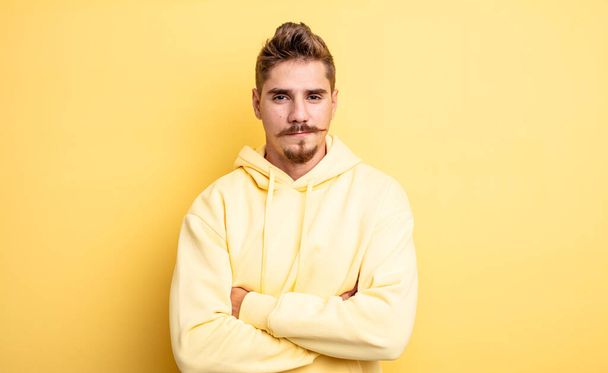 young handsome man feeling displeased and disappointed, looking serious, annoyed and angry with crossed arms. strange moustache concept - Foto, immagini