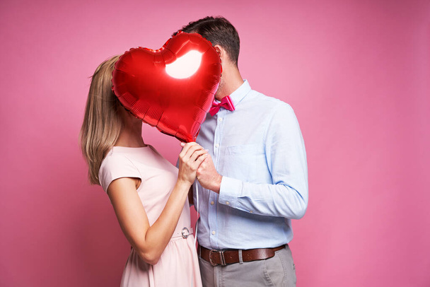 Пара цілує приховані за однією кулькою у формі серця
 - Фото, зображення