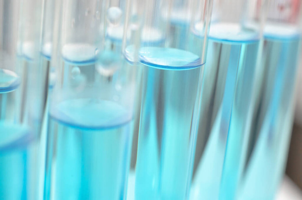 Medische laboratoriumreageerbuizen met blauwe vloeistof close-up, selectieve focus. Wetenschappelijk laboratorium onderzoek. Ontwikkeling van antiviraal vaccin - Foto, afbeelding