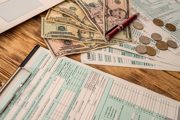 Auf einem Holztisch liegen amerikanische Steuerformulare, amerikanische Dollarscheine und ein Stift. Geschäftskonzept - Foto, Bild