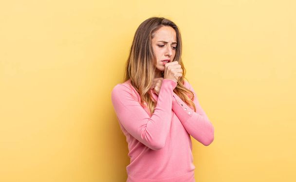 pretty caucasian woman feeling ill with a sore throat and flu symptoms, coughing with mouth covered - Photo, Image