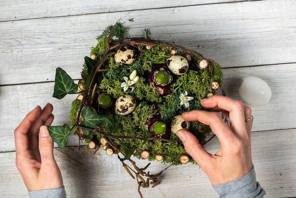 A faceless Caucasian woman creates an Easter composition, plants hyacinth bulbs on a white wooden background. Eco-friendly lifestyle. view from above  - Foto, afbeelding