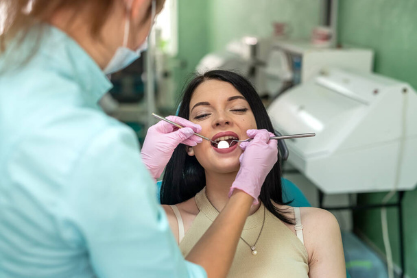 Dentiste professionnel avec outils et uniforme de protection traitant la dent du patient - Photo, image